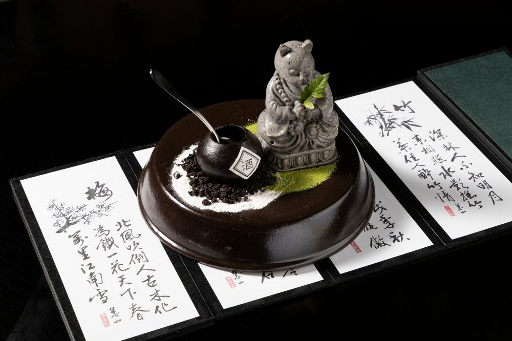 Signature Cat Dessert — a black sesame cat figure served on chocolate soil with matcha
